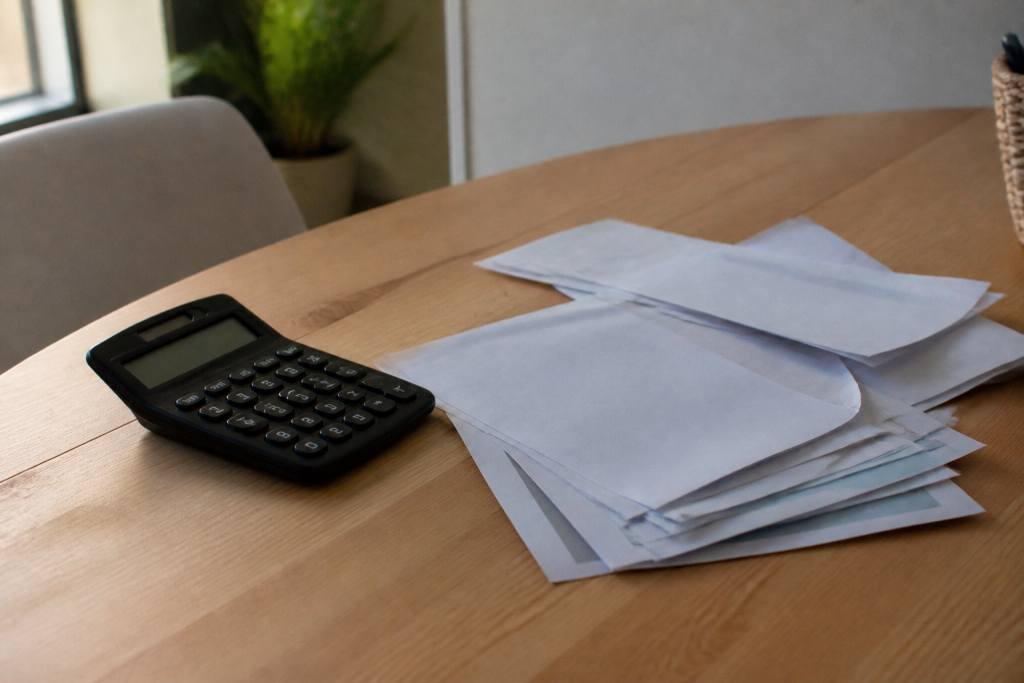 Calculatrice et factures sur un bureau en bois clair