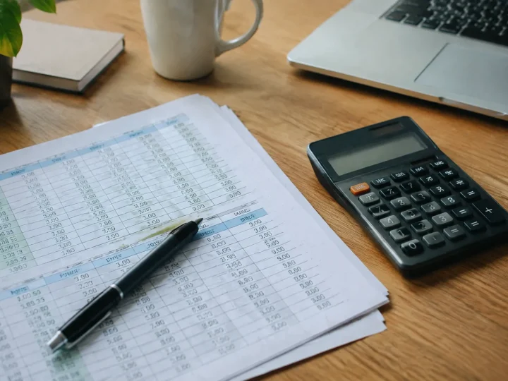 Feuilles de tableur et calculatrice posées sur un bureau