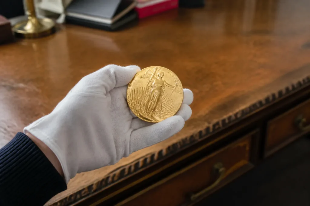 Main gantée tenant une médaille dorée devant un bureau