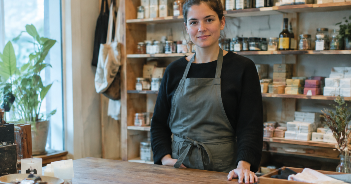 Petite boutique, vendeuse debout derriere son comptoir en bois