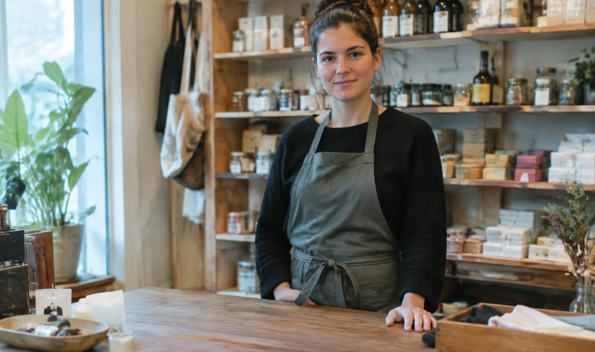 Petite boutique, vendeuse debout derriere son comptoir en bois