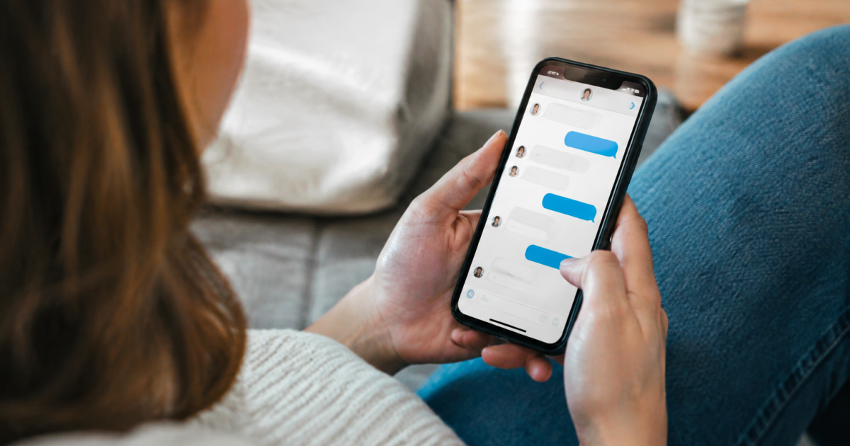 Main tenant un smartphone affichant une conversation de messagerie