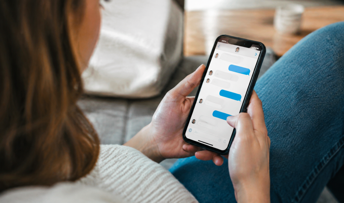 Main tenant un smartphone affichant une conversation de messagerie