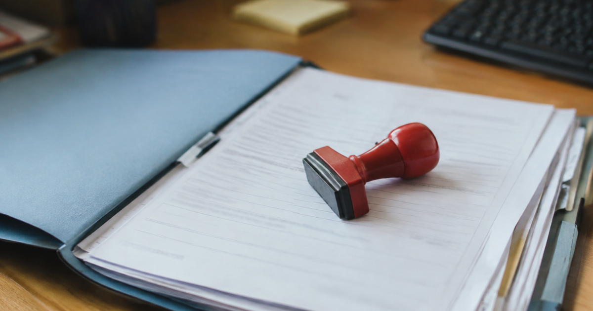 Un tampon rouge pose sur un dossier administratif ouvert