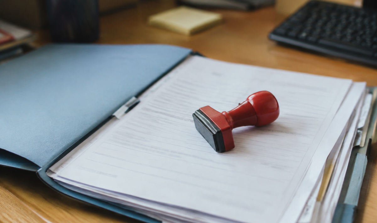 Un tampon rouge pose sur un dossier administratif ouvert